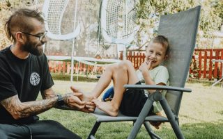 Playful interaction between a father and son in a sunny backyard setting.