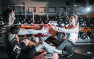 A couple engaged in a fitness session using a medicine ball in a gym environment.