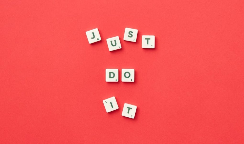 Motivational phrase 'Just Do It' spelled with Scrabble letters on a red background.