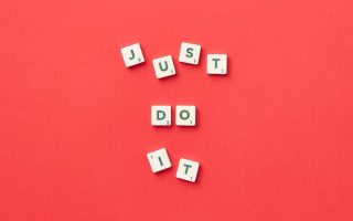 Motivational phrase 'Just Do It' spelled with Scrabble letters on a red background.