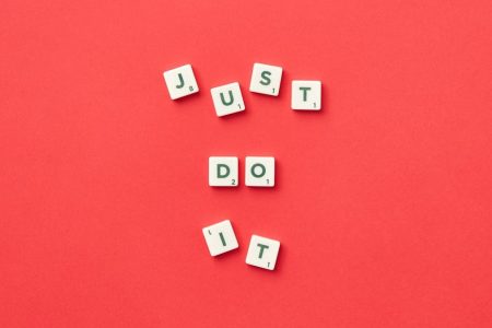 Motivational phrase 'Just Do It' spelled with Scrabble letters on a red background.